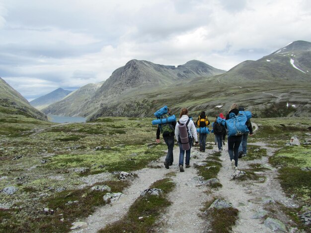 Foto vista posteriore di persone che camminano sulla montagna contro il cielo