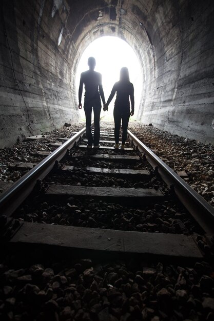 Rear view of people walking on railroad track