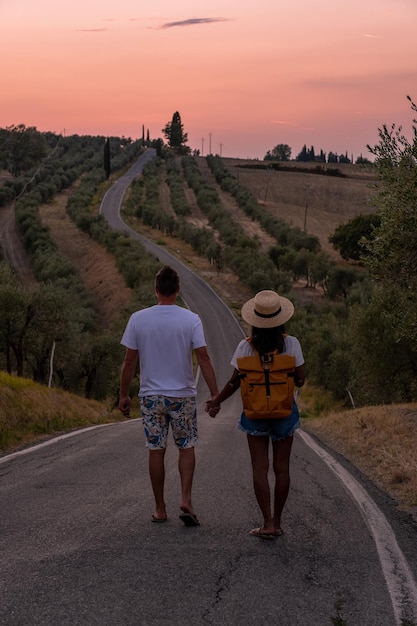 Rear view of people walking on road against sky during sunset