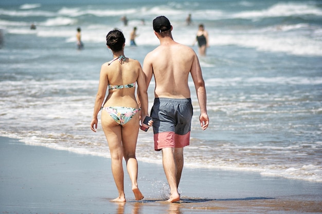 Photo rear view of people walking on shore at beach