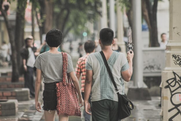 Rear view of people walking on street in city