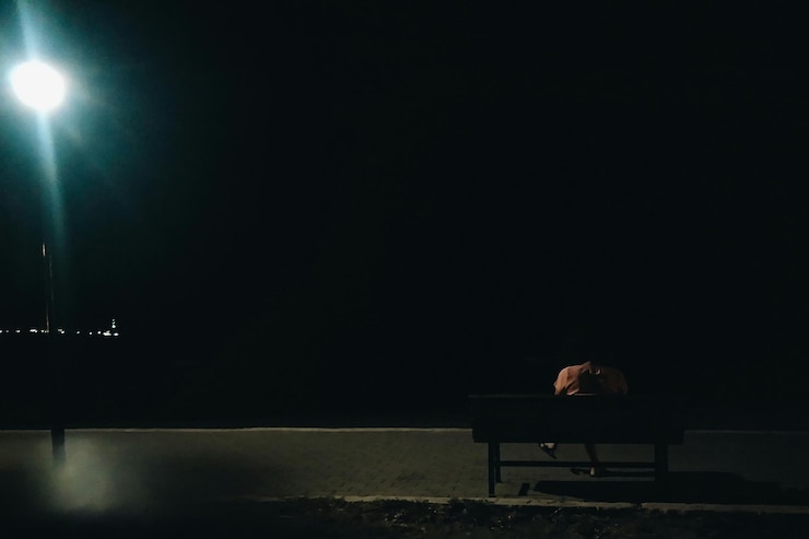 Photo rear view of person sitting on park bench at night