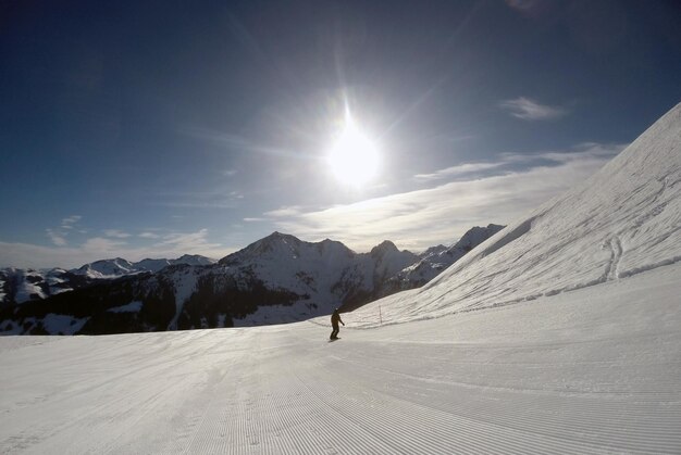 Rear view of person snowboarding on snowcapped mountain against sky