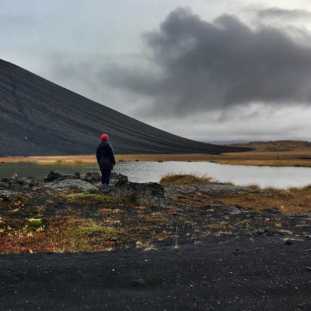 Foto vista posteriore di una persona in piedi vicino al lago contro il cielo a hverfjall