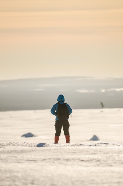 Foto vista posteriore di una persona in piedi su un terreno coperto di neve