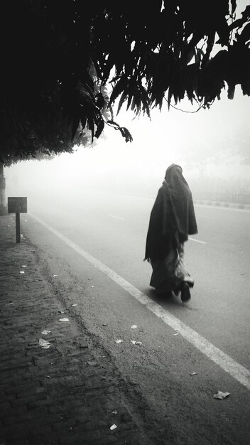 Foto vista posteriore di una persona che cammina sulla strada durante il tempo nebbioso