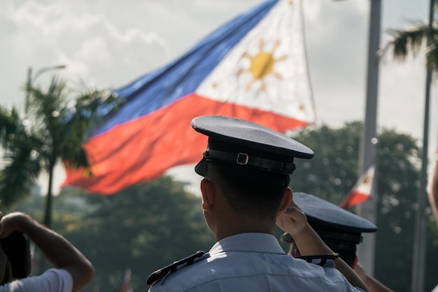 Photo rear view of police saluting philippines flag