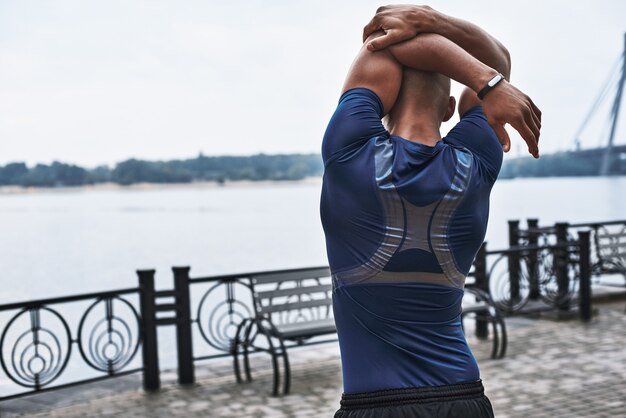 Rear view portrait of an african sportive man who is stretching hands