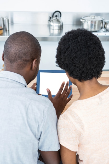 Rear view of pregnant couple looking at digital tablet in kitchen