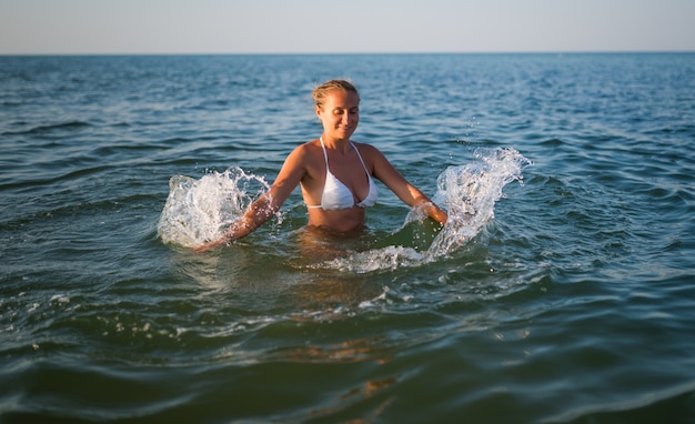 화창한 따뜻한 여름날 바다에서 수영하는 예쁜 젊은 여성의 뒷모습. 휴식과 관광 여행의 즐거움의 개념. 카피스페이스