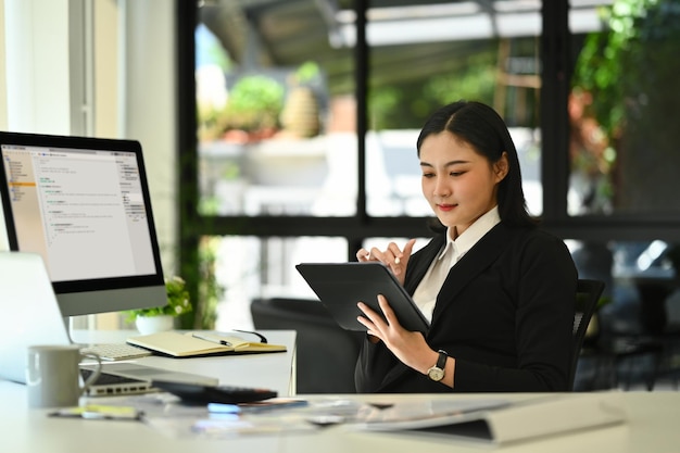 Rear view programer asian woman working on digital tablet