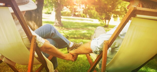 公園のデッキチェアに座ってリラックスした成熟したカップルの背面図