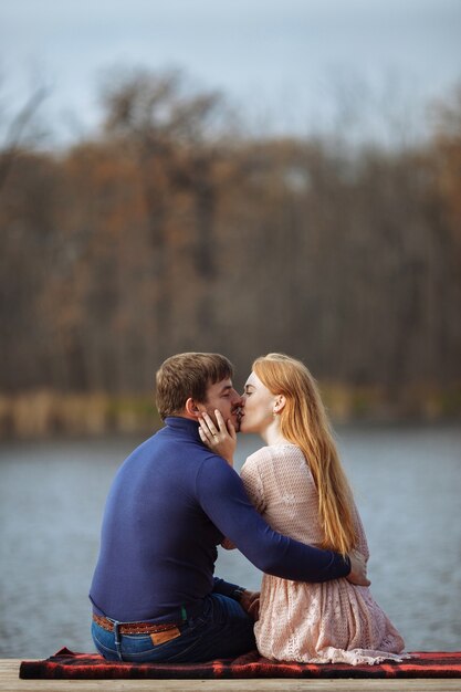 Rear view of romantic young couple sitting on pier enjoying amazing view