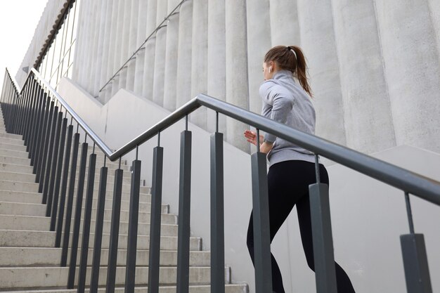 Foto vista posteriore dell'atleta corridore in esecuzione sulle scale. la forma fisica della donna è fare jogging all'aperto.