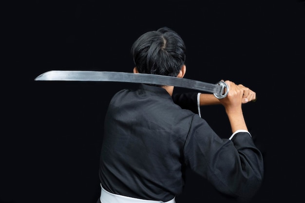 Rear view of a Samurai warrior holding the sword with a black background