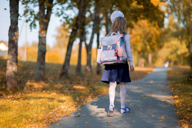 rear view of schoolgirl walking on footpath at park during autumn