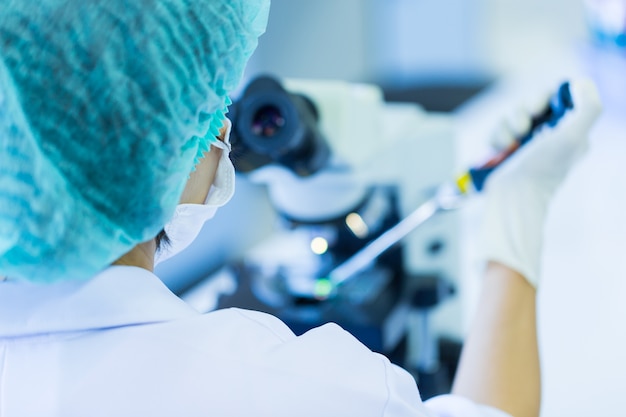 Rear view of Scientist using a microscope in a laboratory