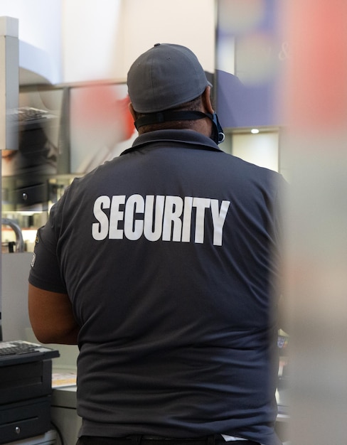 Photo rear view of a security guard in uniform patrolling in a commercial building.