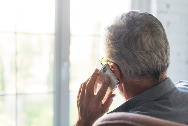 Foto retrovisione dell'uomo senior che per mezzo del cellulare