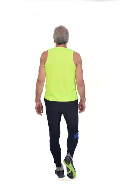 白い背景の上を歩くスポーツウェアを持つ年配の男性の背面図