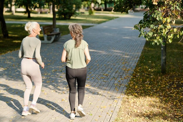 Photo rear view of senior women running along the path in the park