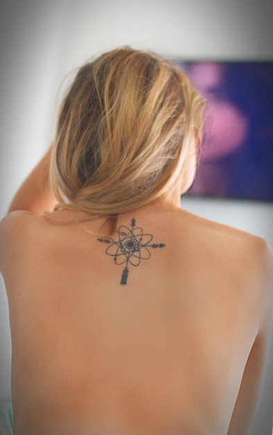 rear view of sensuous topless woman with tattoo on back