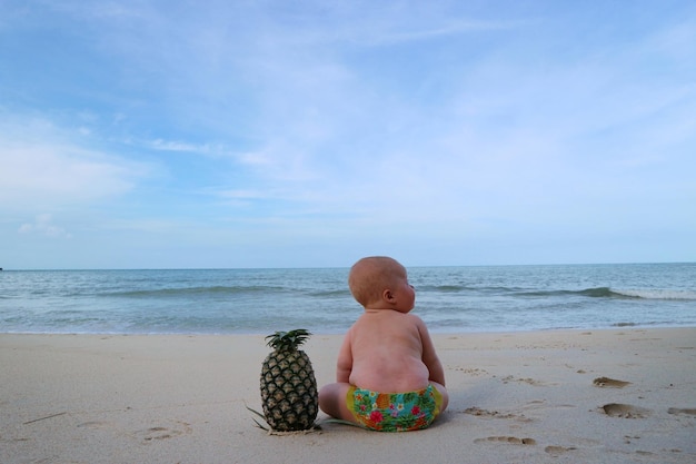 Rear view of shirtless boy on beach against sky