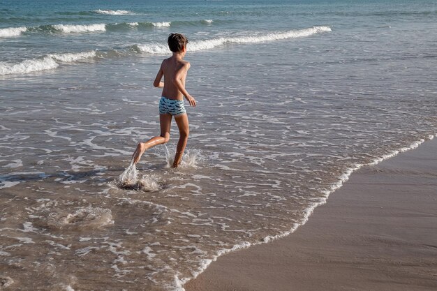 Photo rear view of shirtless boy running at beach