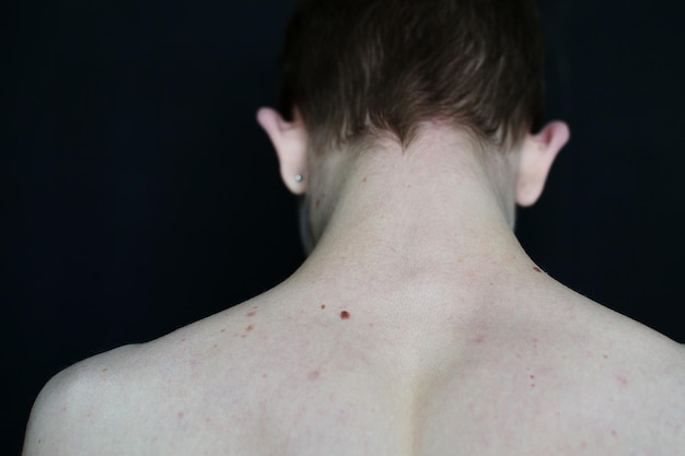 rear view of shirtless man against black background