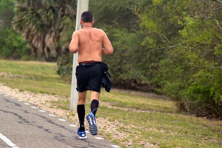 Photo rear view of shirtless man running on road