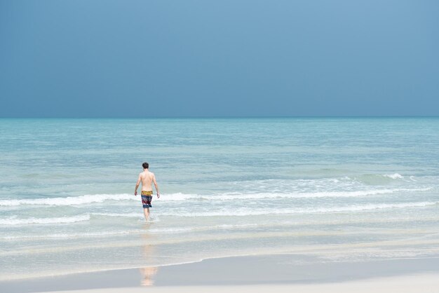 해변 에 서 있는 셔츠 없는 남자 의 뒷면