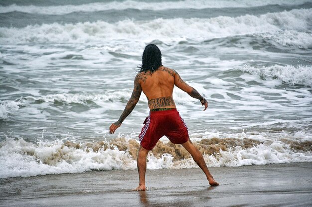 Foto vista posteriore di un uomo senza camicia che vaga in mare