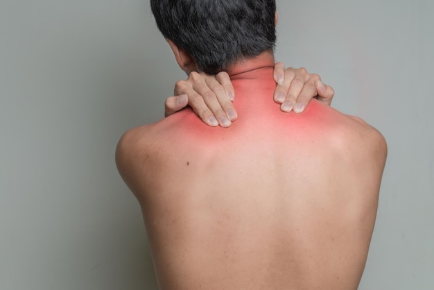 Foto vista posteriore di un uomo senza camicia con dolore alla spalla sullo sfondo grigio