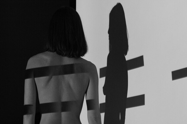 Photo rear view of shirtless woman standing by wall