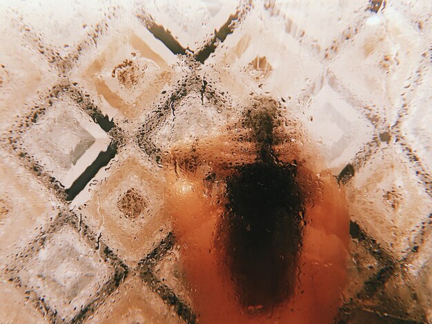 Photo rear view of shirtless woman taking bath seen through wet glass