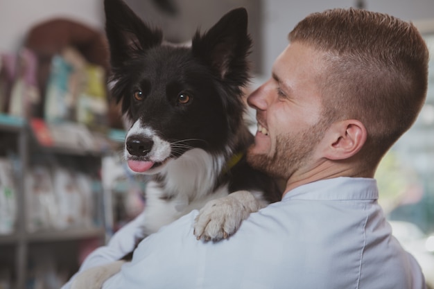 Rear view shot of a handsome cheerful male veterinarian holding adorable healthy dog