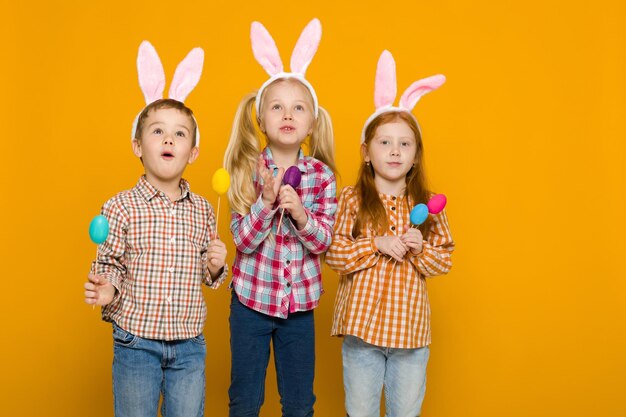 Rear view of siblings with toys against yellow background