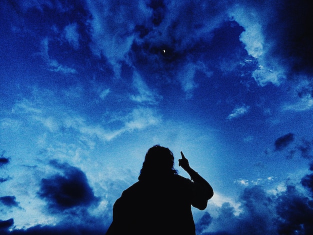 Photo rear view of silhouette man pointing at sky