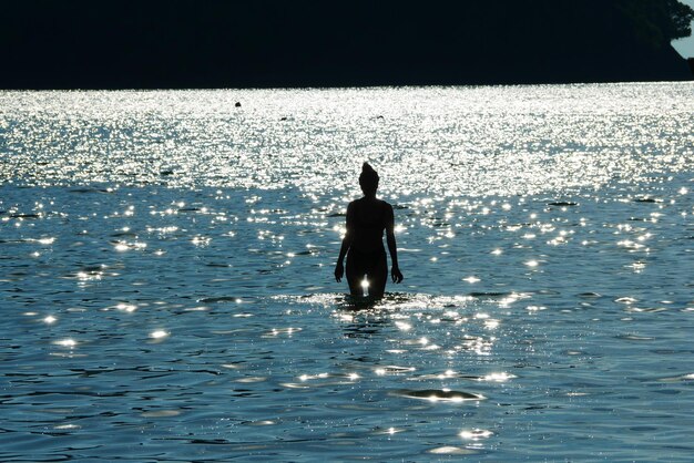 Foto vista posteriore di un uomo a silhouette in mare contro il cielo