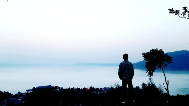 Rear view of silhouette man standing against sky