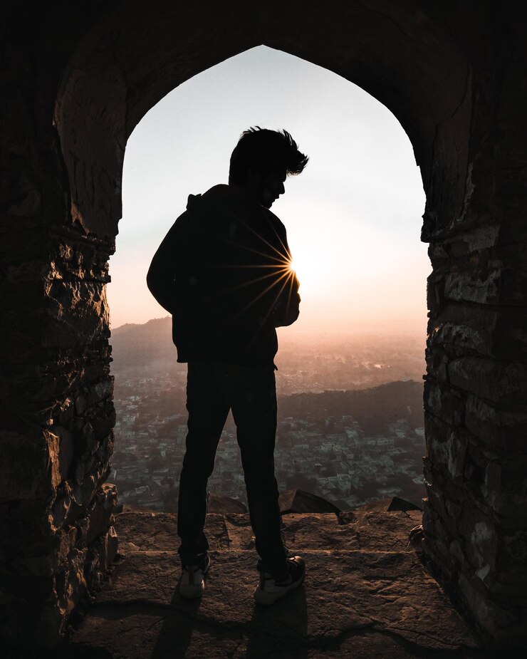फोटो rear view of silhouette man standing by entrance against sky during sunset