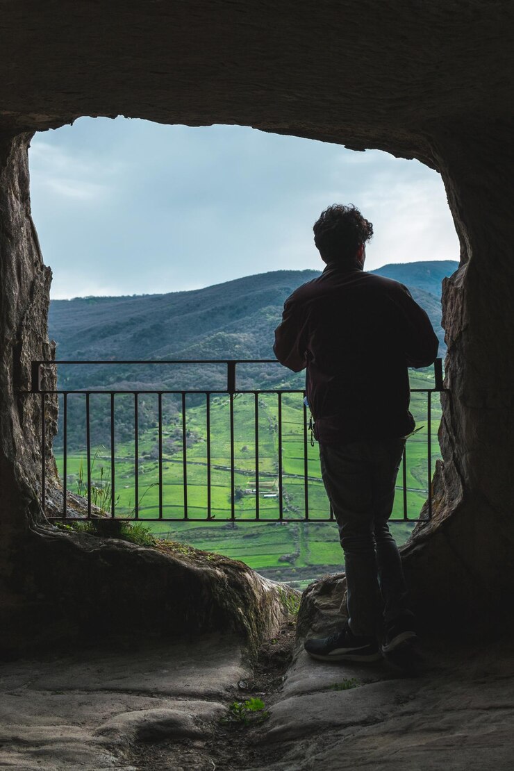 Photo rear view of silhouette man standing in cave against mountain