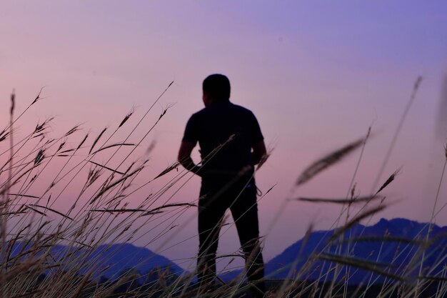 Rear view of silhouette man standing on field against sky