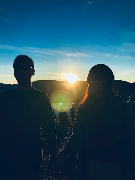 Rear view of silhouette man standing on mountain against sky during sunset