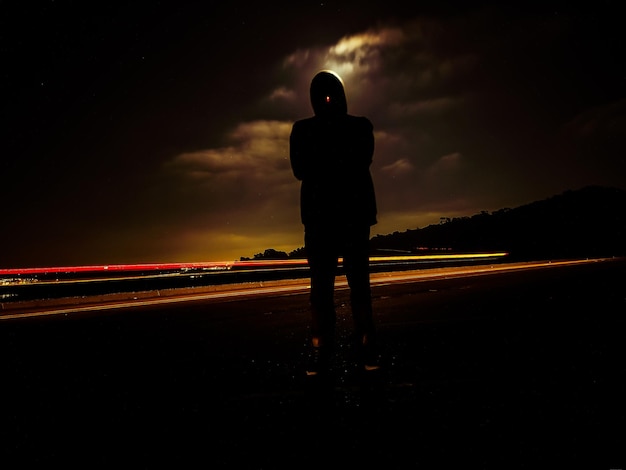 Photo rear view of silhouette man standing on road at night