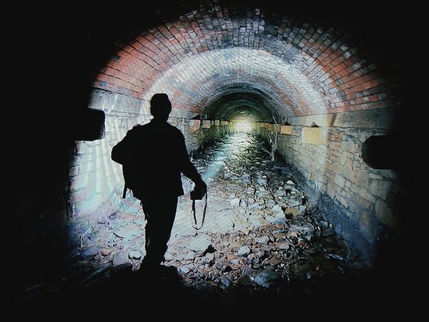 Foto vista posteriore di un uomo in silhouette in piedi nel tunnel