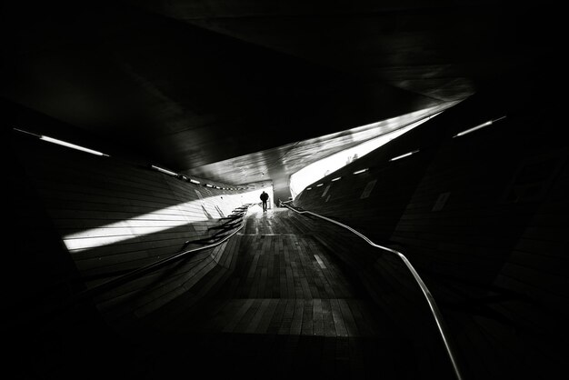 Задний вид силуэта человека, идущего по дороге в туннеле