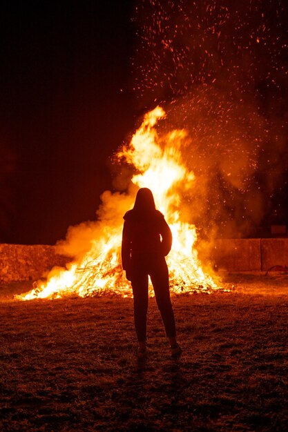 Foto vista posteriore di un uomo a silhouette con i cracker di fuoco di notte