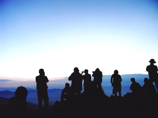 Photo rear view of silhouette people on cliff at sunset