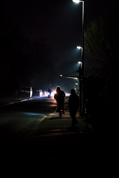 Foto vista posteriore di persone a silhouette sulla strada illuminata di notte